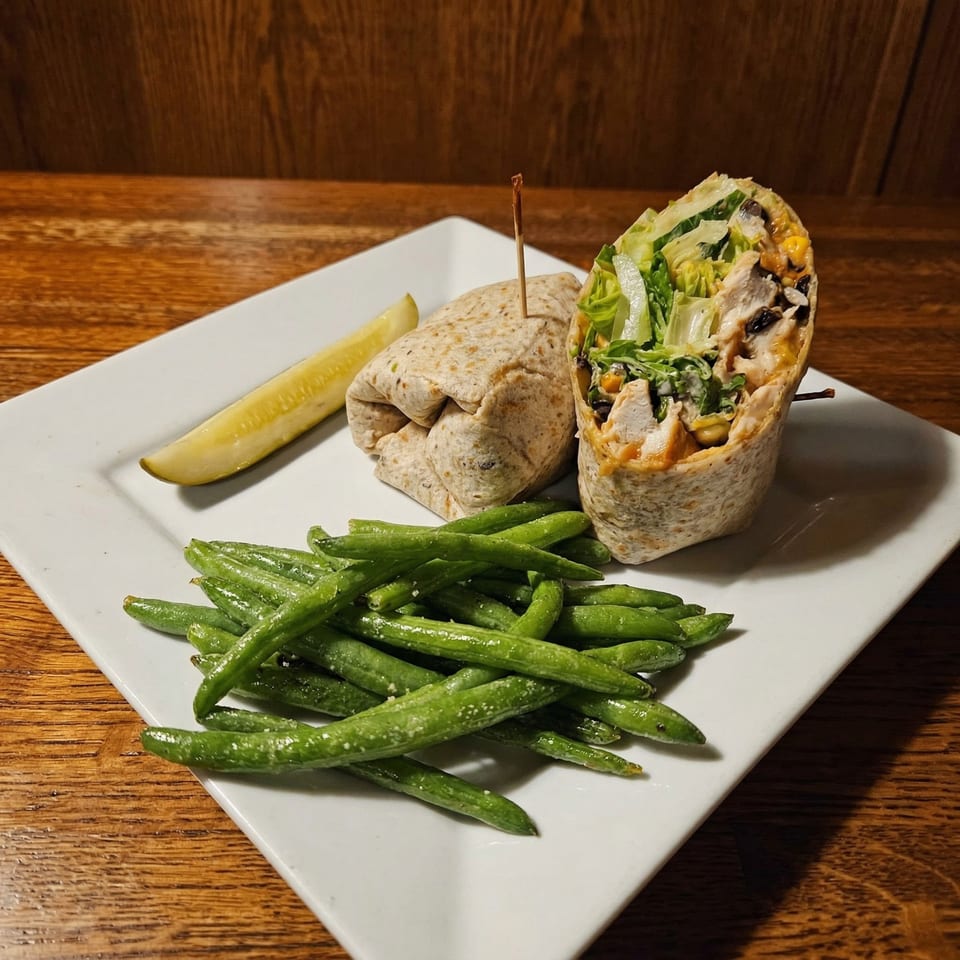 Chicken wrap with lettuce, corn, and black beans, served with green beans and a pickle spear.