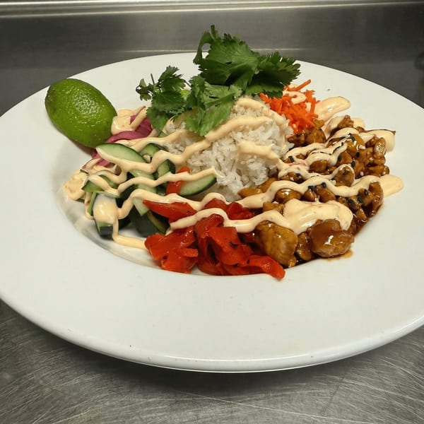 A.T. The Black & White's American dish with rice, chicken, vegetables, and sauce on a white plate.